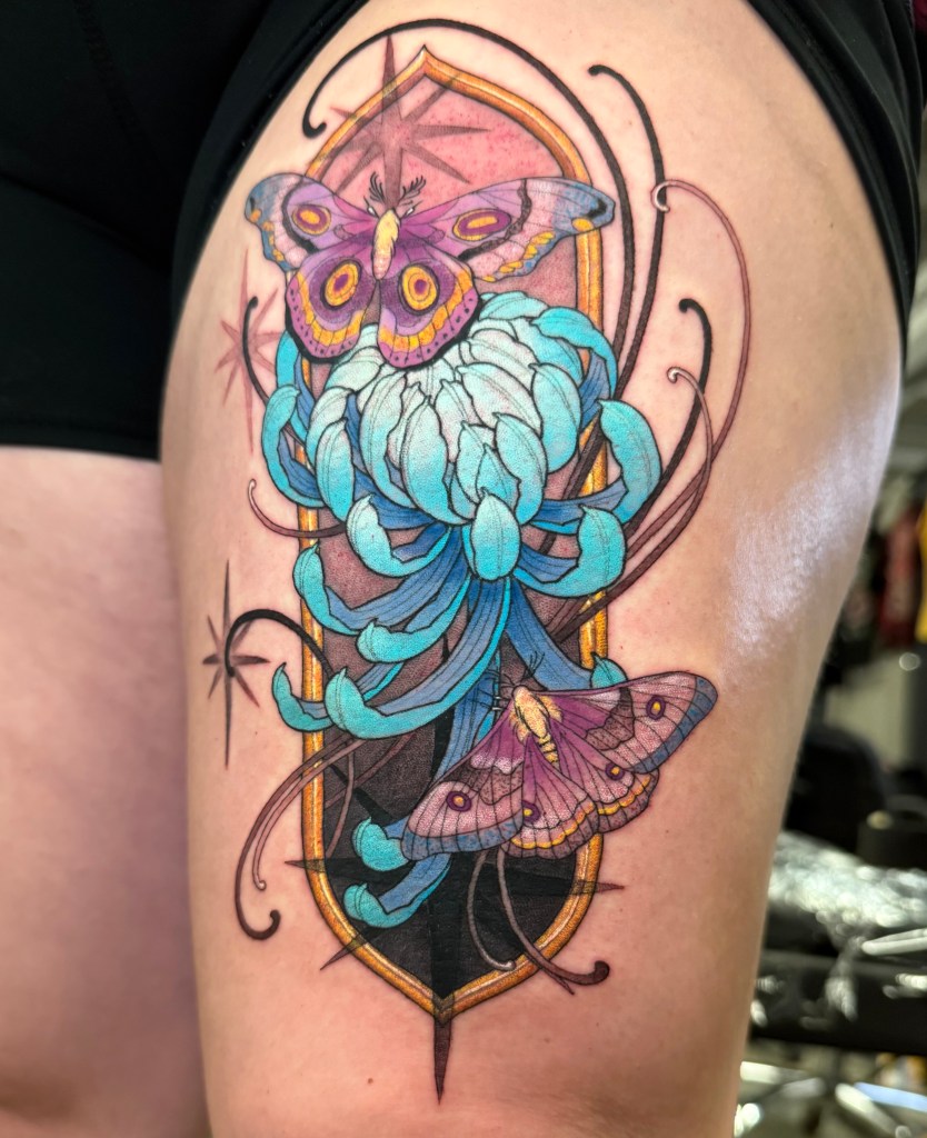 Tattoo by Liz Ignatius. Frame containing a chrysanthemum and moths.
